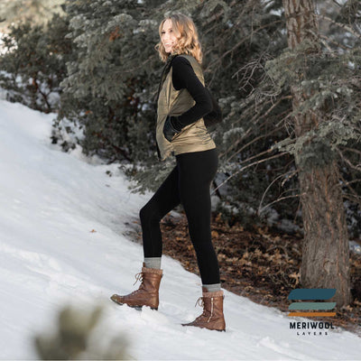 woman in the snow wearing a pair of women's black merino wool 400 heavyweight base layer bottoms