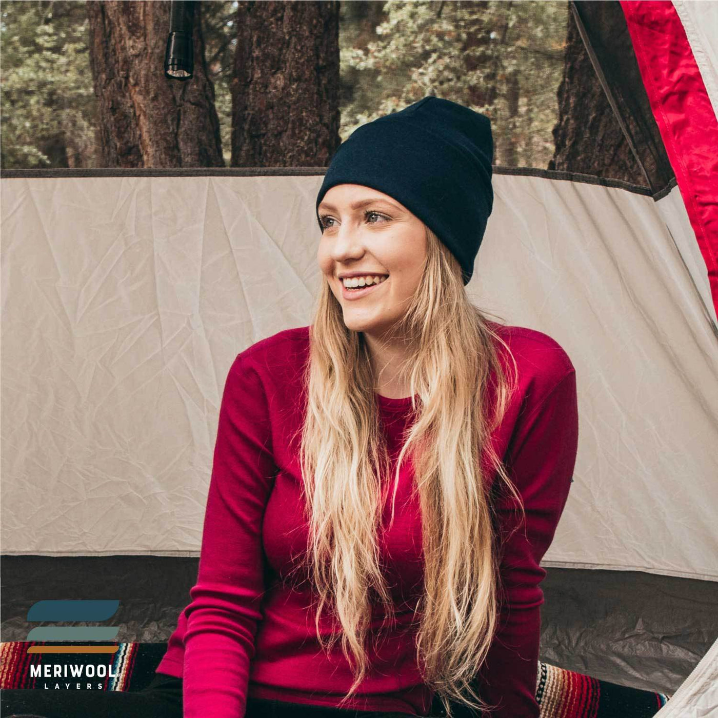 woman in a tent camping wearing a navy blue merino wool 250 cuffed beanie
