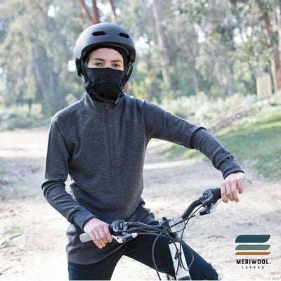 teenager on a bike wearing a black merino wool 200 youth balaclava face mask with a helmet